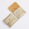 A tan and beige PU leather jewelry pouch with a secure snap button closure.