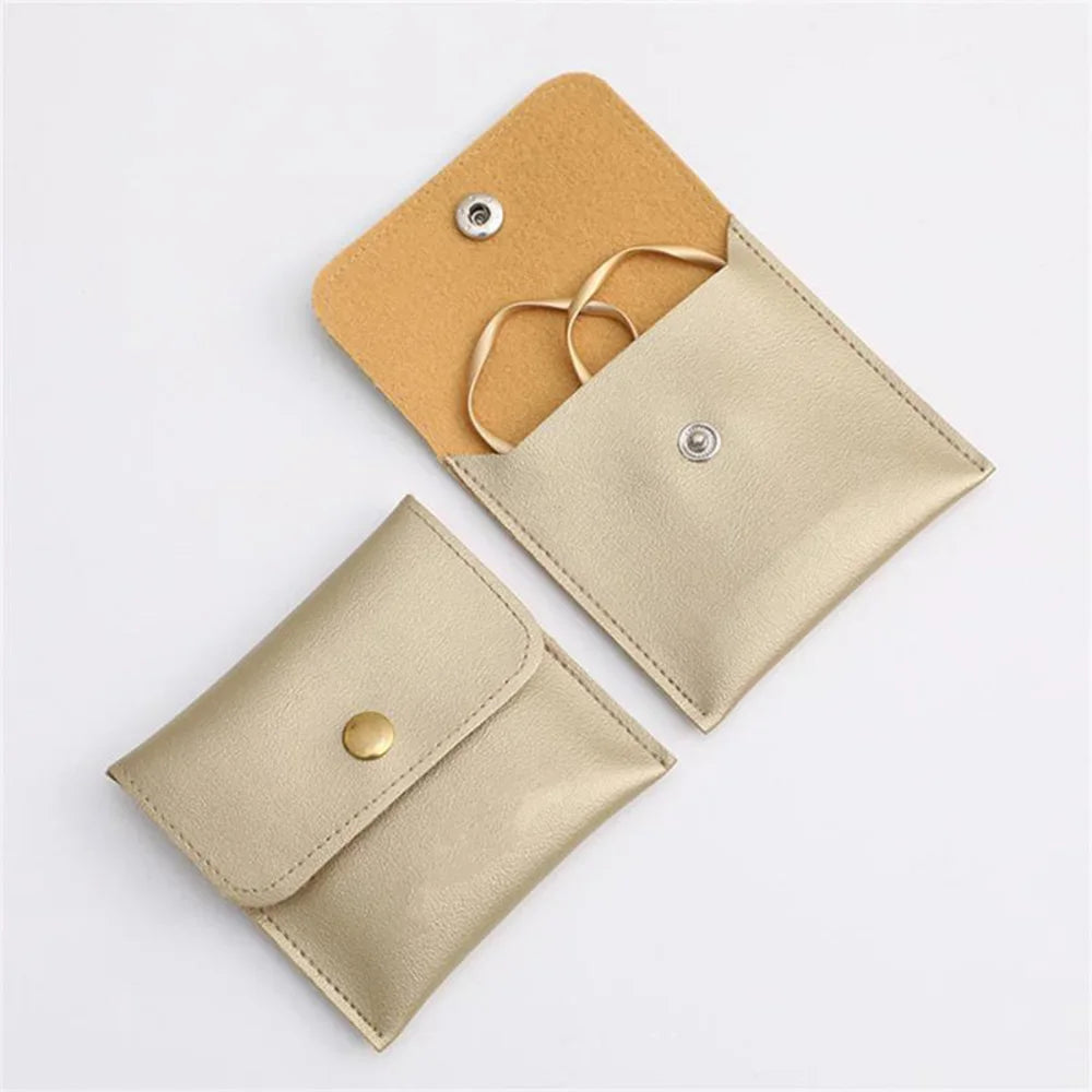 A tan and beige PU leather jewelry pouch with a secure snap button closure.
