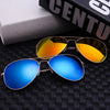 A pair of men's aviator sunglasses with gold and silver frames resting on a dark surface next to a book.