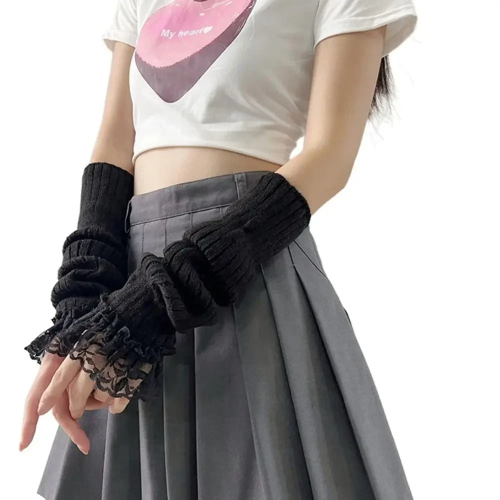 A person wearing a white t-shirt and gray pleated skirt is modeling black fingerless arm warmers.