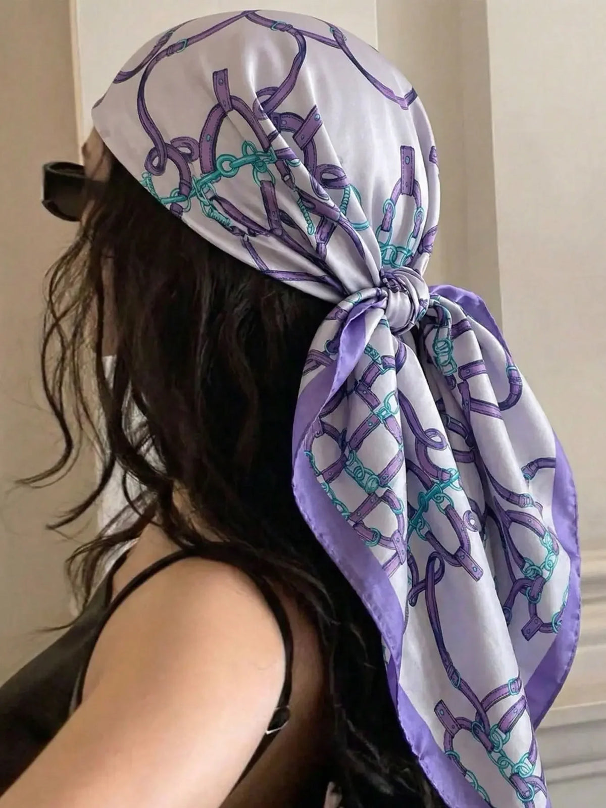 A woman wearing a purple and white floral satin shawl tied around her head, viewed from the back.