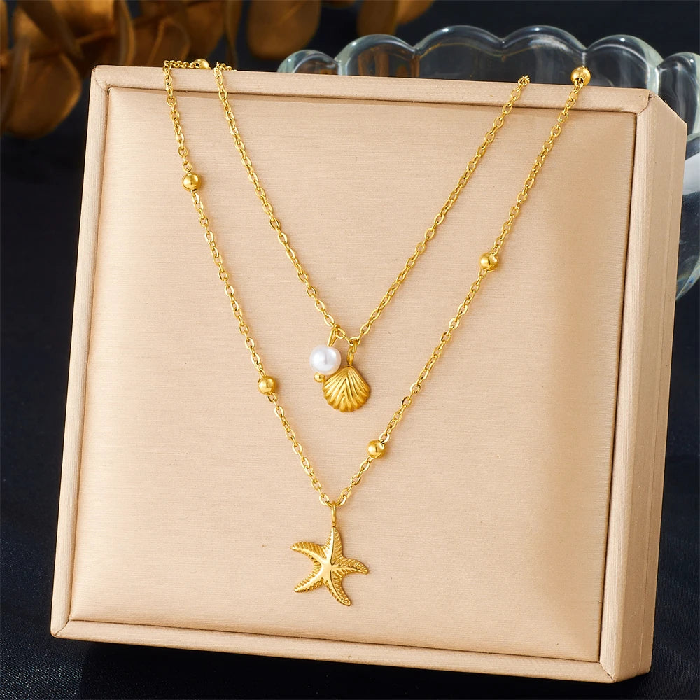 Gold stainless steel necklace featuring a starfish heart pendant on a delicate chain, presented in a light pink box.