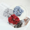 Three colorful knitted hair scrunchie headbands in navy blue and red polka dots displayed on a white plate.