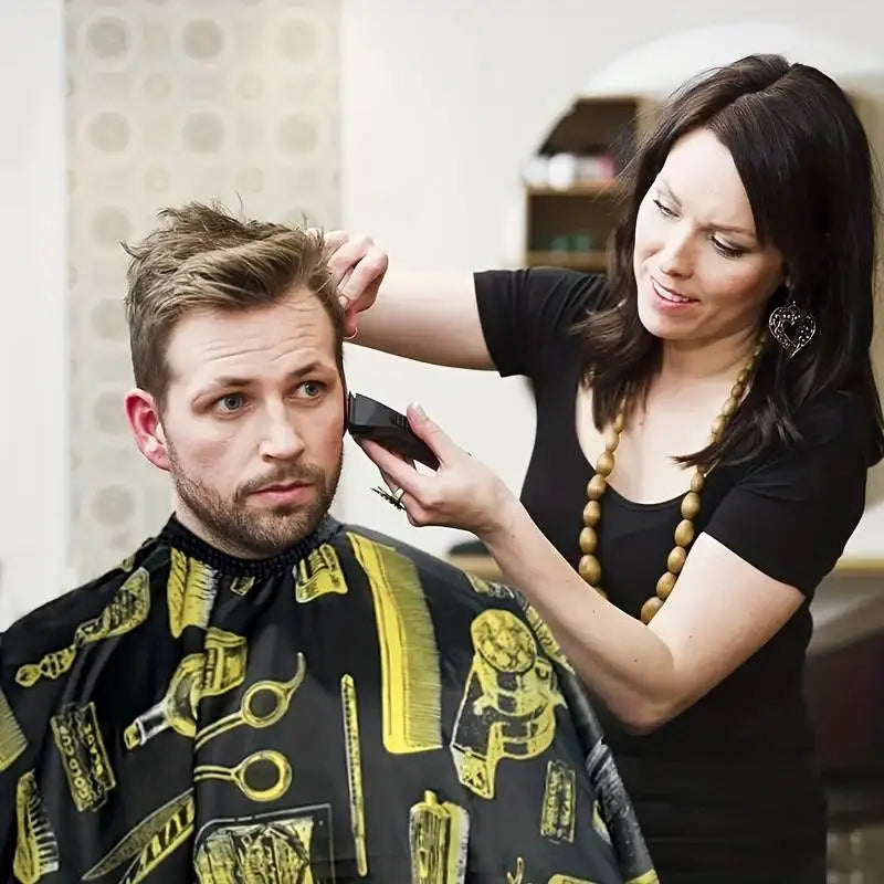 A woman is adjusting a professional hair cutting and styling apron on a man's shirt.