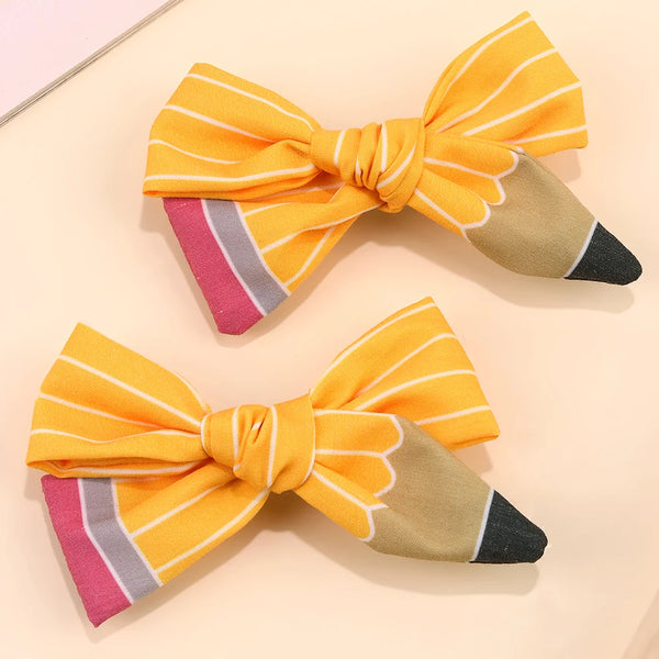 A set of orange and yellow striped fabric bow hair clips with a beige accent.