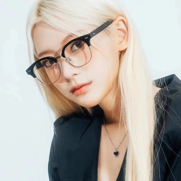 A close-up portrait of a woman wearing black eyeglasses with clear lenses against a white background.