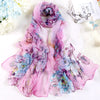 Écharpe en soie florale rose et violette transparente drapée sur fond blanc.