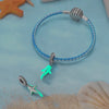 Sterling silver devil's eye charm bracelet with a silver sphere and a turquoise charm on a light blue background