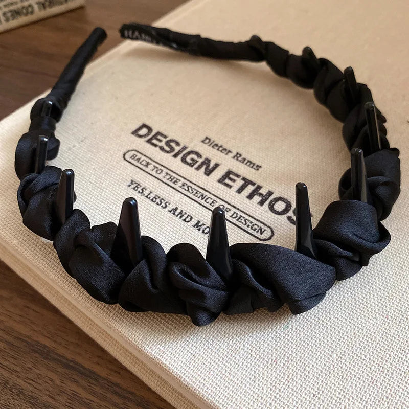 Black resin wave toothed headband resting on a light-colored book.