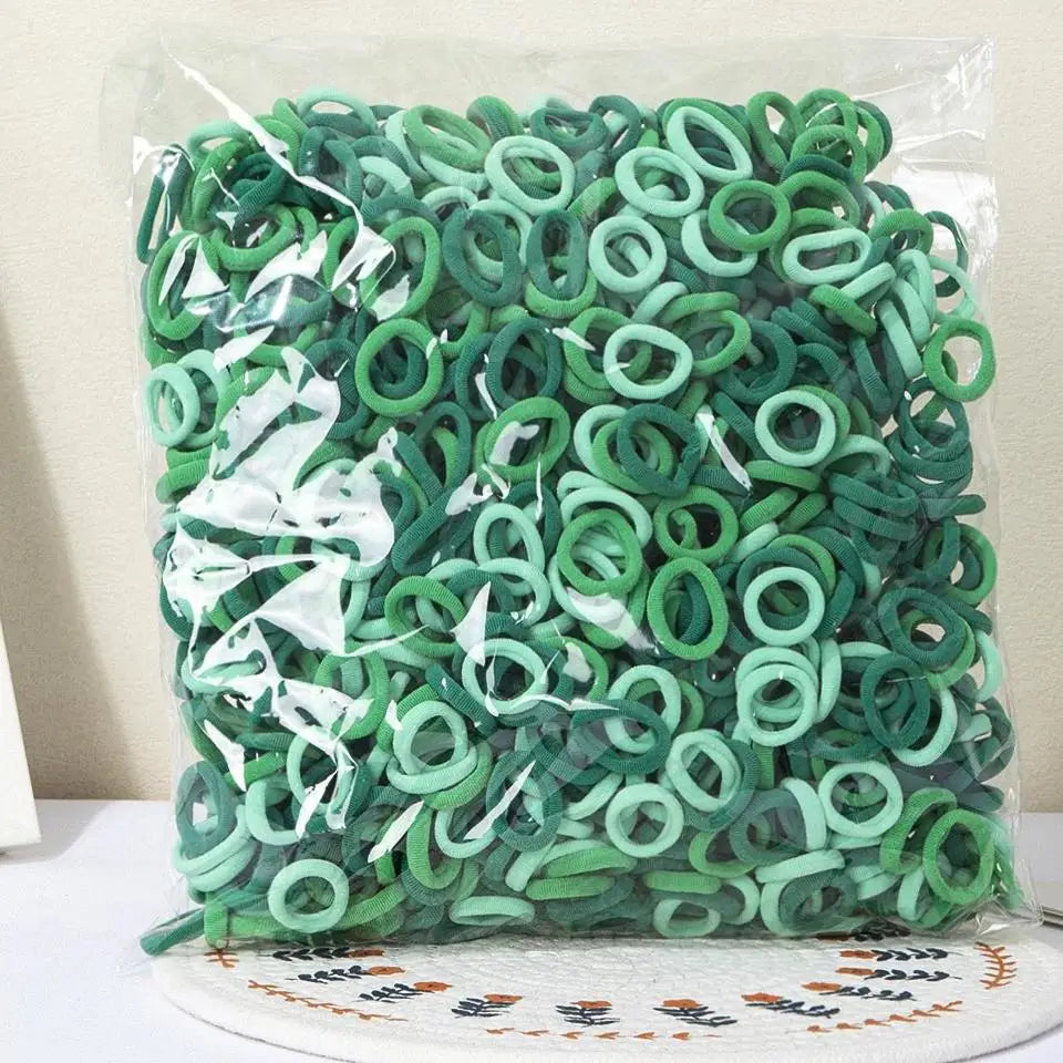 A bundle of green nylon elastic hair cords for kids headbands packaged in clear plastic.