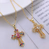 A dainty gold cross charm necklace with colorful gemstones displayed on a white background.