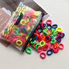 A pile of colorful elastic hair bands in various neon and bright colors is shown next to a clear plastic pouch.