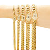 A display of five gold-plated Miami Cuban chain necklaces with diamond accents worn on a wrist.