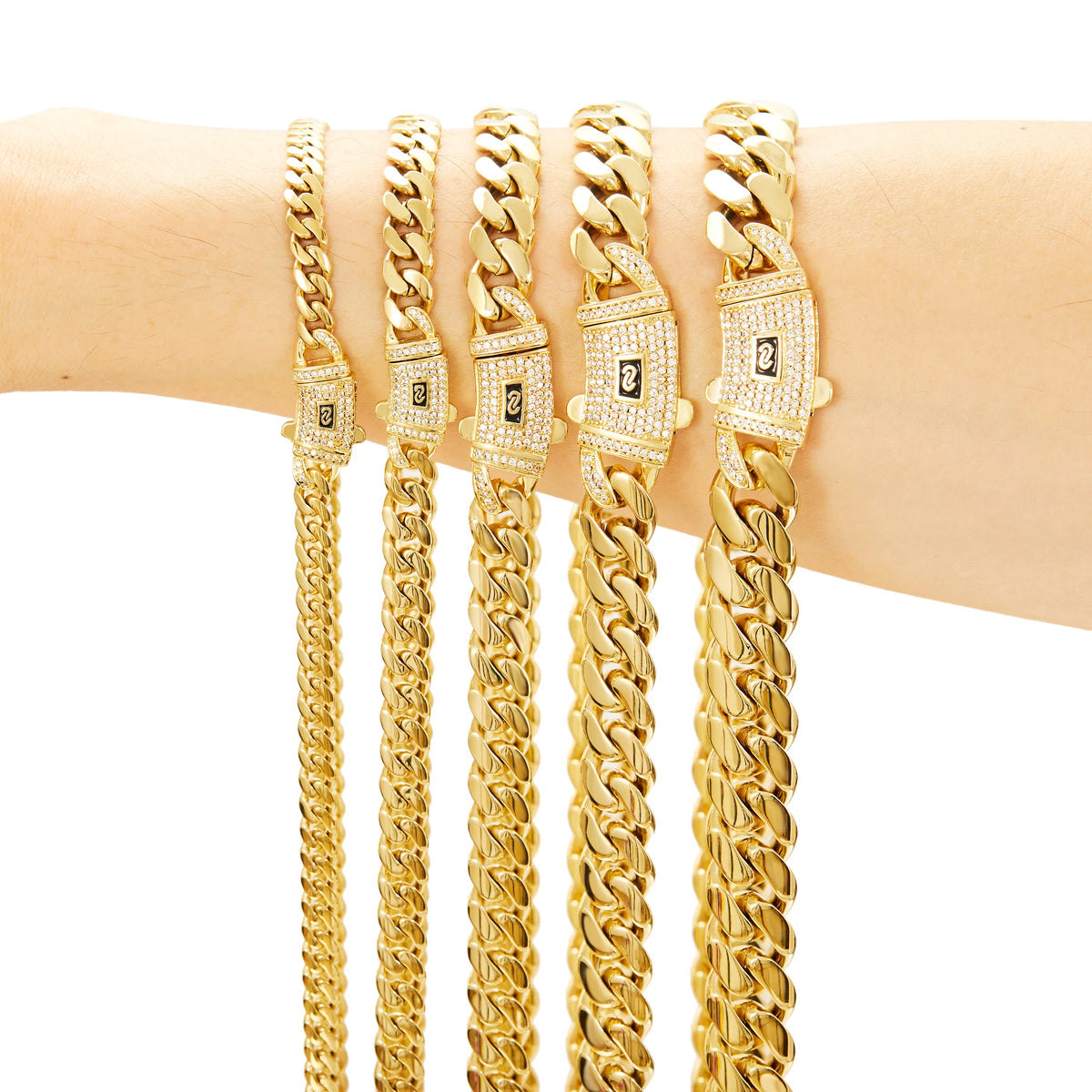 A display of five gold-plated Miami Cuban chain necklaces with diamond accents worn on a wrist.