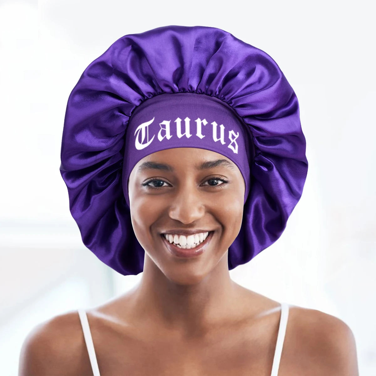A woman wearing a purple satin sleep bonnet with a Taurus wrap band.