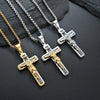 Tres collares de cruz de Jesús plateados y dorados exhibidos sobre una superficie oscura.