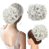 A woman shows off a light gray synthetic curly chignon hairstyle, including a close-up of the hairpiece.
