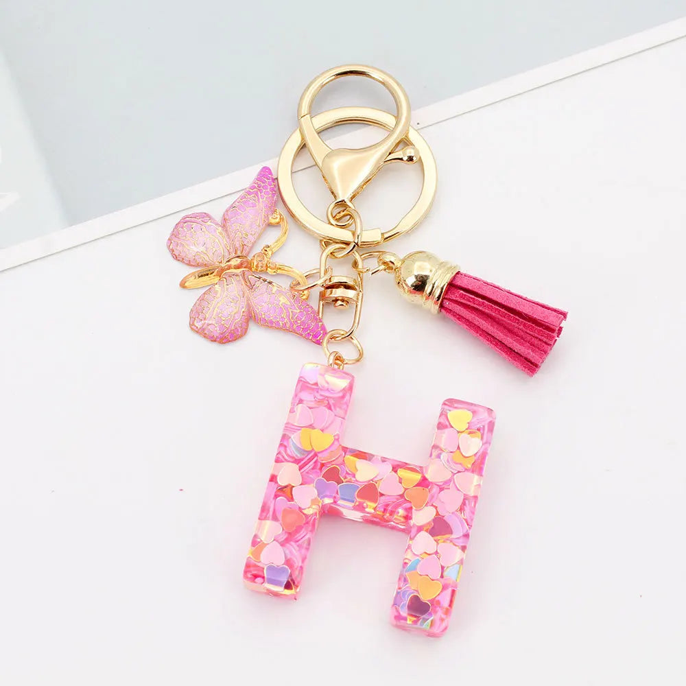 Alphabet letter acrylic keychain shaped like the letter H with pink butterfly and magenta tassel