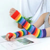 A colorful striped knitted fingerless sleeve worn on a person's arm, resting near some papers.
