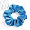 A close-up shot of a set of six blue velvet scrunchies for hair ties
