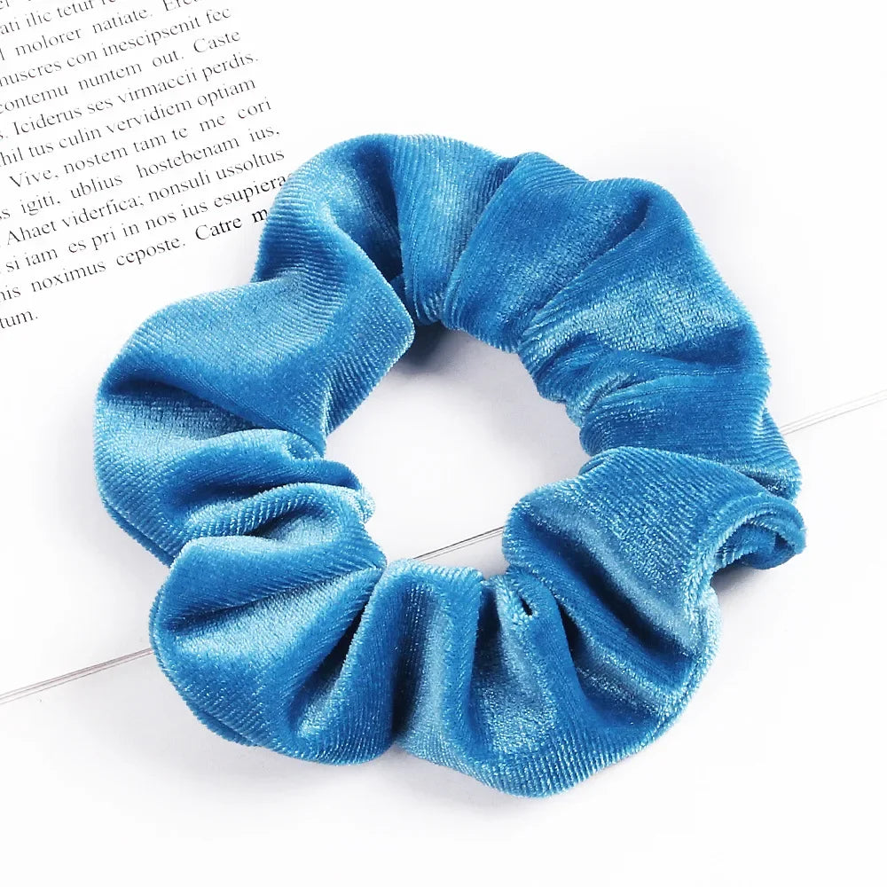 A close-up shot of a set of six blue velvet scrunchies for hair ties