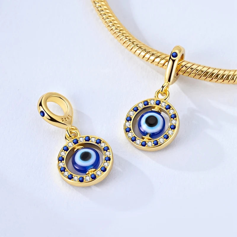 A gold-toned charm bracelet featuring a devil's eye design with blue and silver accents.