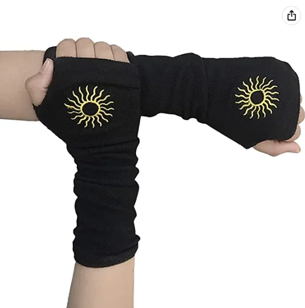 Black knitted fingerless gloves with golden sun designs worn on a hand.