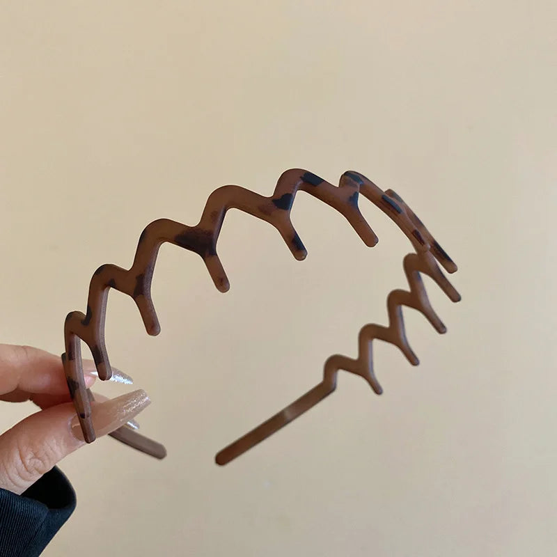 A close-up of a brown resin wave toothed headband for women, featuring a wavy design.