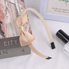 A light beige grosgrain ribbon hair bow is displayed next to a black cosmetic product and a box.