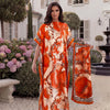 An orange tropical floral leopard print abaya scarf worn by a model outdoors near a white building.