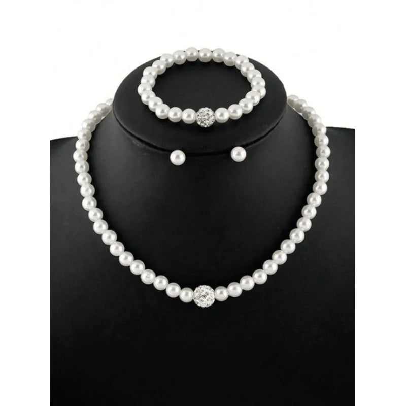 A necklace and earrings set featuring faux pearls displayed on a black jewelry stand.