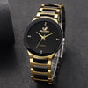 A close-up shot of a gold-toned analog quartz watch with a black face and black strap on a dark background.