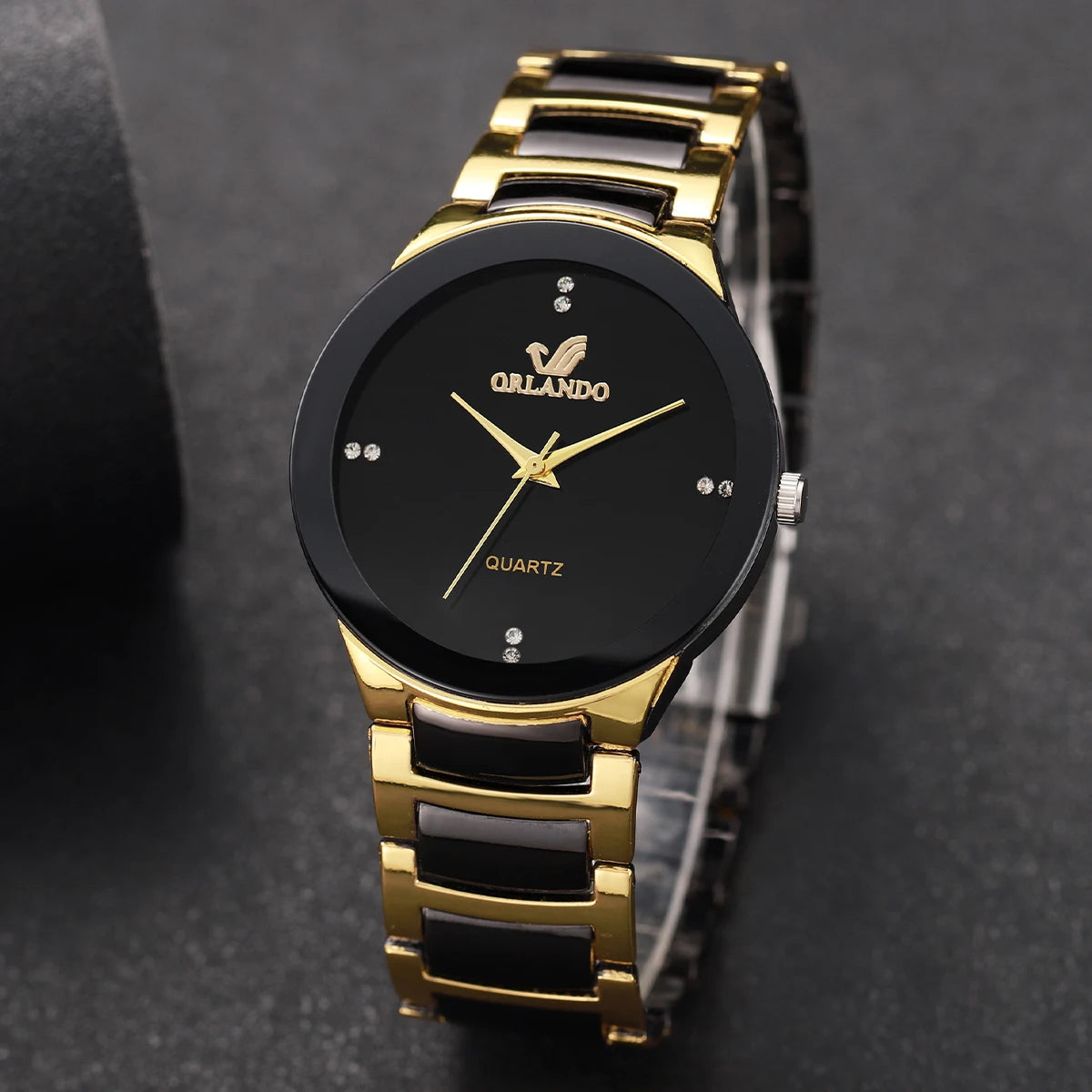 A close-up shot of a gold-toned analog quartz watch with a black face and black strap on a dark background.