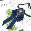 A dark blue luxury rhinestone bow tie neck tie displayed on a white background with green foliage.