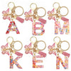 Alphabet letter acrylic keychains in pink and multicolored floral designs with pink tassels