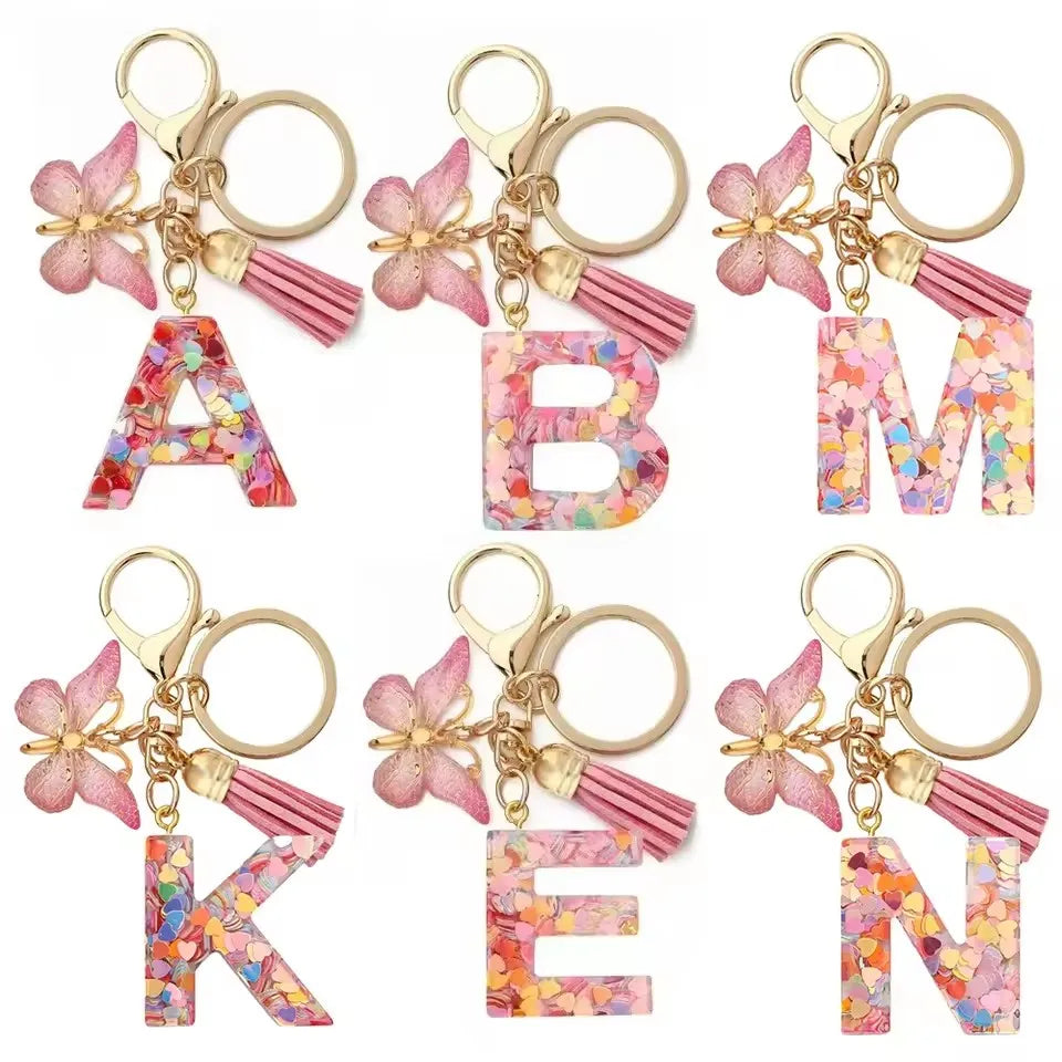 Alphabet letter acrylic keychains in pink and multicolored floral designs with pink tassels