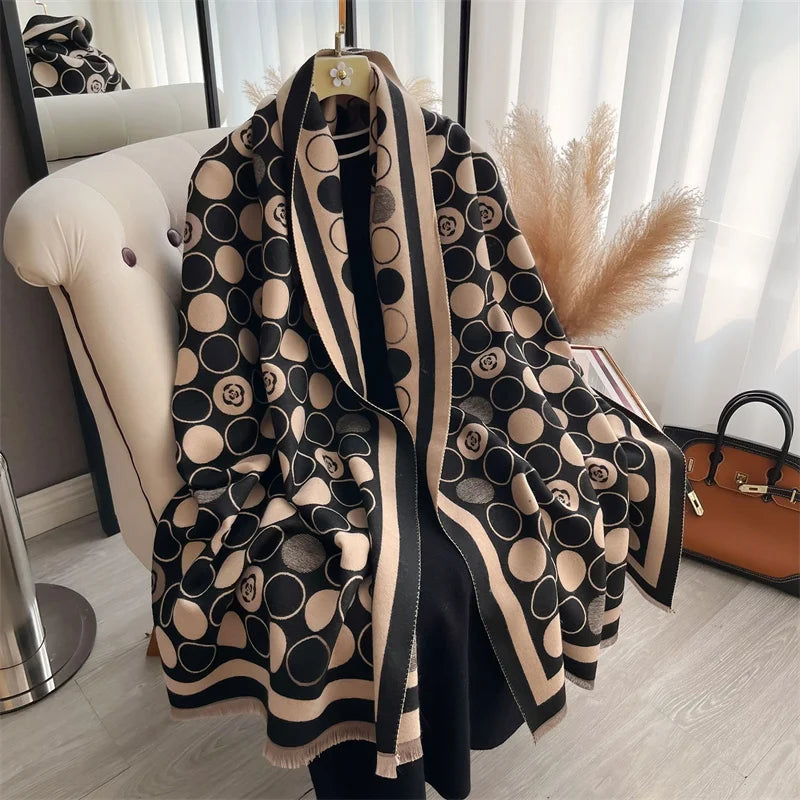 A black and beige patterned cashmere scarf draped over a hanger in a bright room.