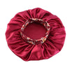 A deep red satin sleep bonnet with a floral pattern and an elastic band.