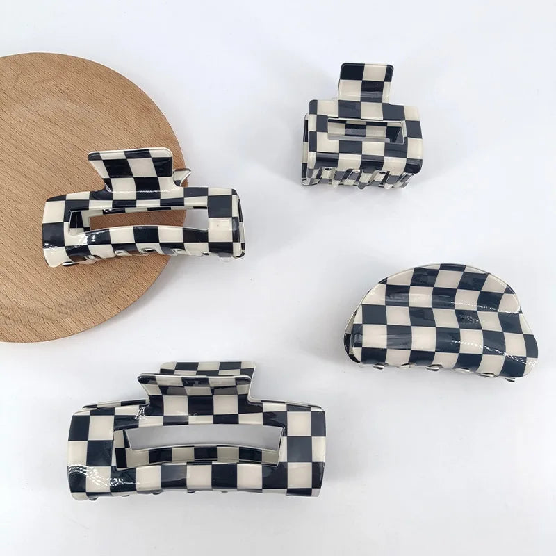 A set of black and white checkered rectangle hair claw clips displayed on a wooden surface.