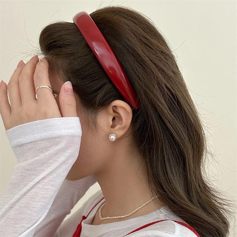 A woman shows her face with her hand while wearing a red PU leather fashion headband.
