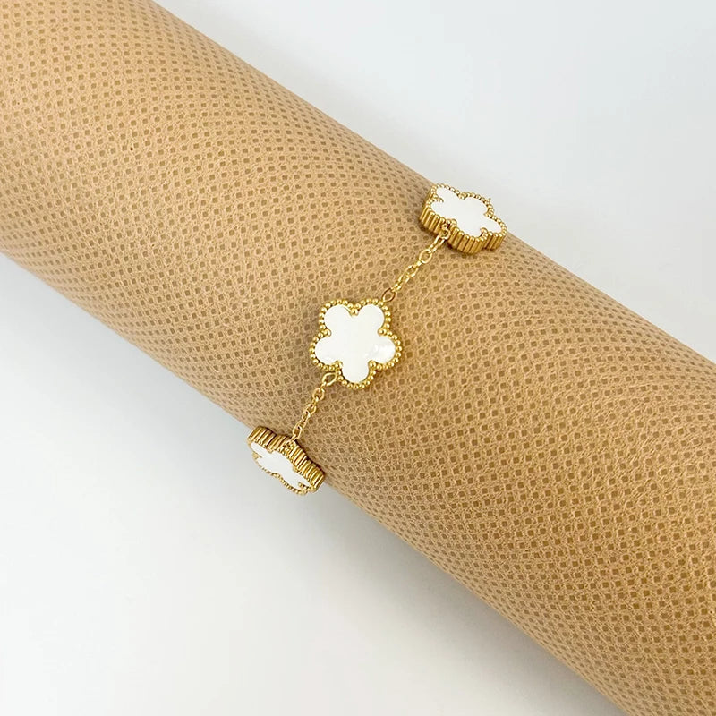 Gold plated stainless steel double-sided petal bracelet displayed on a beige textured background.