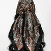 A dark floral satin shawl tied in a decorative knot, featuring intricate patterns in brown, black, and olive green tones.