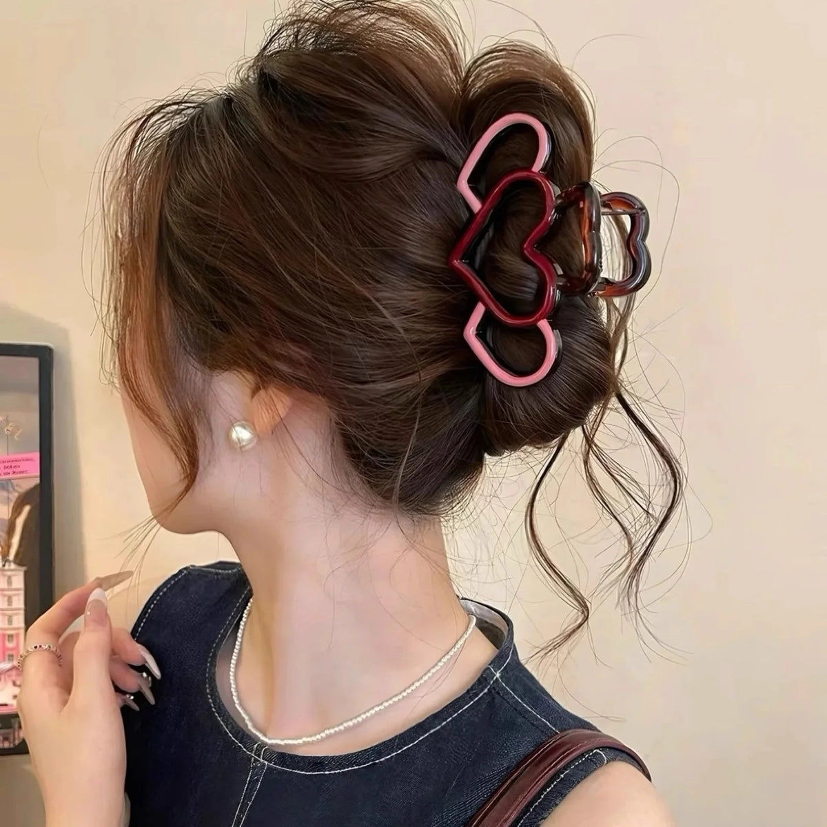 A woman shows off a hairstyle featuring pink heart-shaped hair claws and a delicate silver necklace.