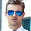 A man wearing blue mirrored aviator sunglasses outdoors.