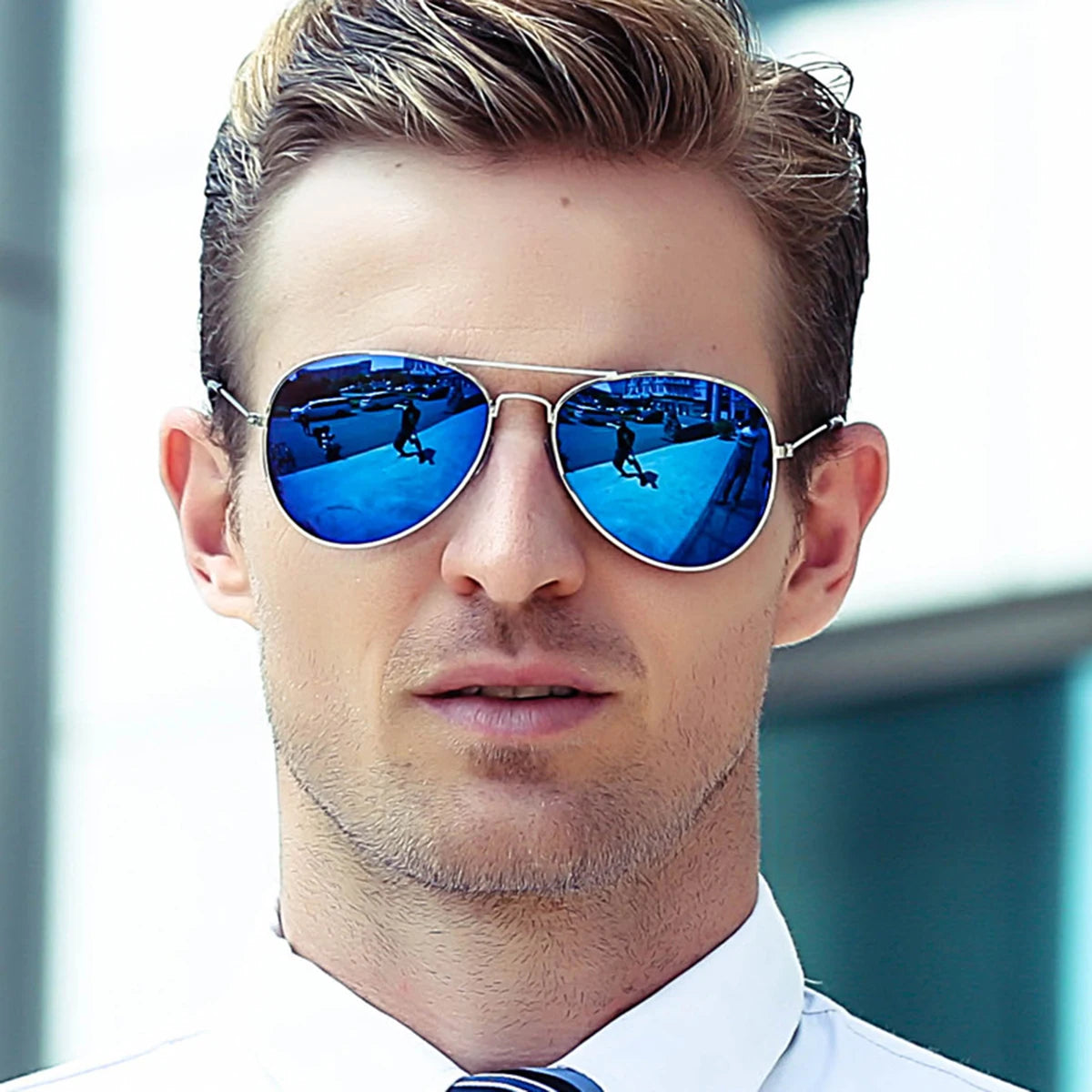 A man wearing blue mirrored aviator sunglasses outdoors.