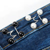 Silber- und perlmuttfarbene verstellbare Bundverlängerungsknöpfe auf blauem Jeansstoff.