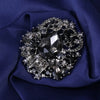 Broche florale en cristal élégante avec une grande pierre centrale entourée de cristaux scintillants sur fond bleu foncé