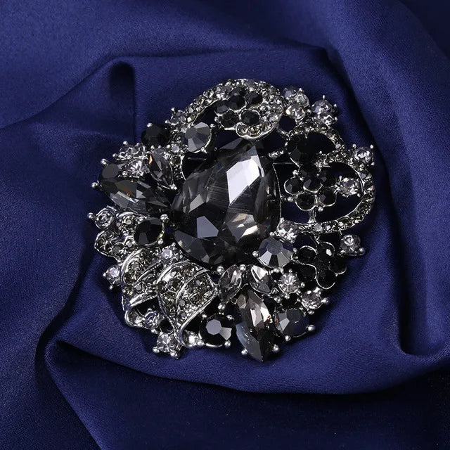 Broche florale en cristal élégante avec une grande pierre centrale entourée de cristaux scintillants sur fond bleu foncé