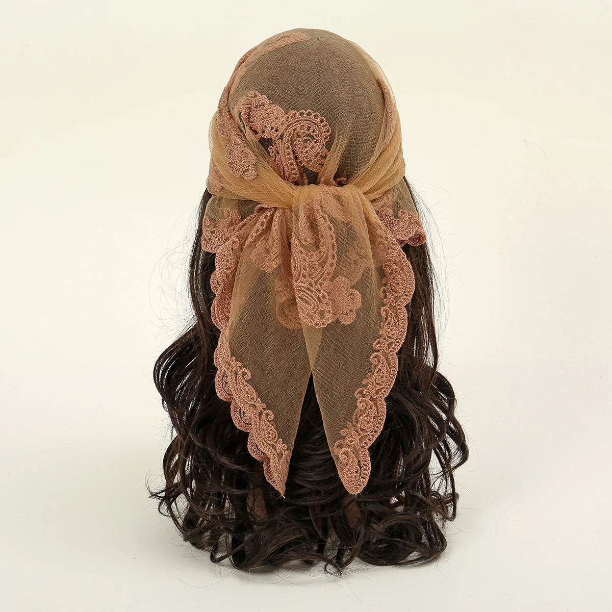 A brown floral embroidered lace bandana headscarf tied around dark, curly hair.