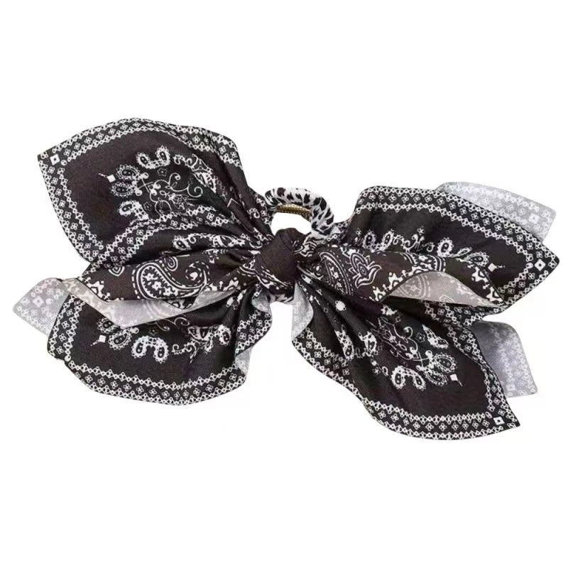 Pinza de cabello vintage elegante con tela negra y patrón de anacardo intrincado y detalles blancos.